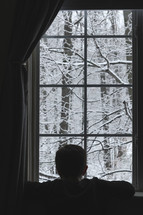 child watching snow out a window 