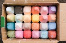 A cardboard box full of colorful sidewalk chalk.