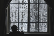 a child watching snow out a window 