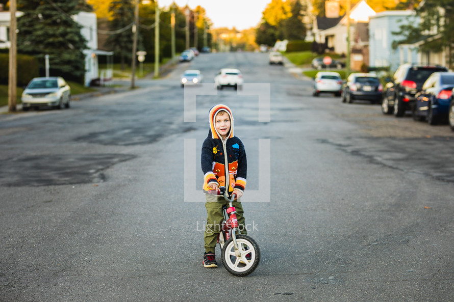 boy outdoors in a sweater riding a bike 