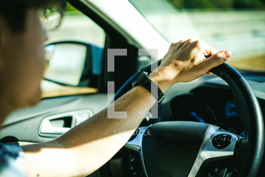 man's hand on a steering wheel 