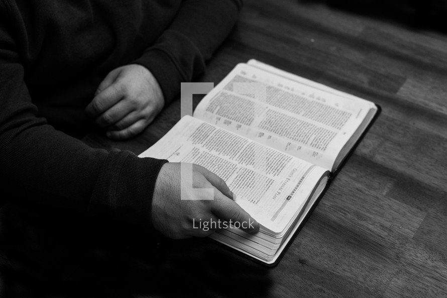 a man sitting at a table reading a Bible 