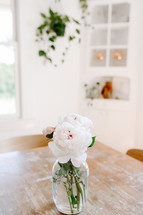 peonies in a vase on a wood table 