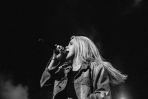 teen girl singing into a microphone at a concert 