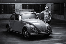 a man leaning against a vintage Volkswagen Beetle 