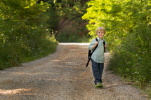 child with a backpack on a dirt road 