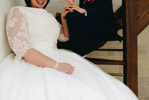 bride and military groom holding hands sitting on steps 
