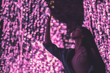 a girl touching pink Christmas lights 