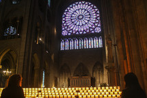 a woman lighting a prayer candle in a cathedral 