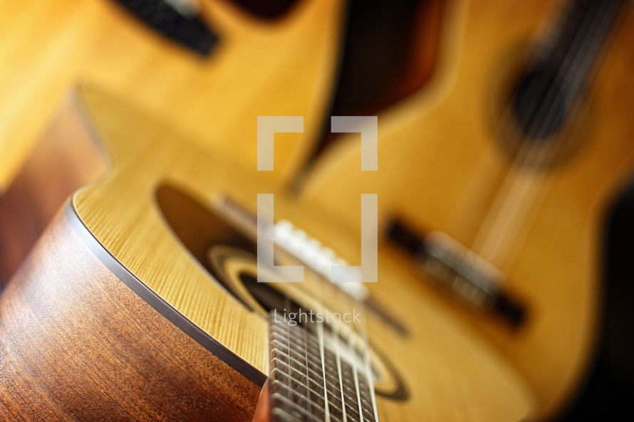 A trio of acoustic guitars (standard six string in foreground, classical six string and a twelve string in background) are combined to create a music themed image that can signify more traditional worship bands, praise songs, church music, etc. - shallow depth of field on foreground six string. 