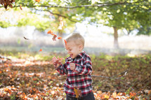 laughing child playing in leaves 