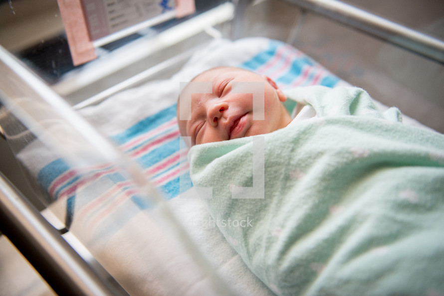 A newborn infant in a hospital bassinet.