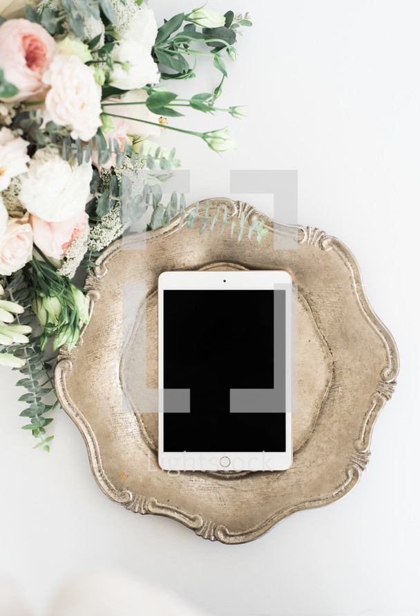 iPad on a silver tray and bouquet of pink flowers 