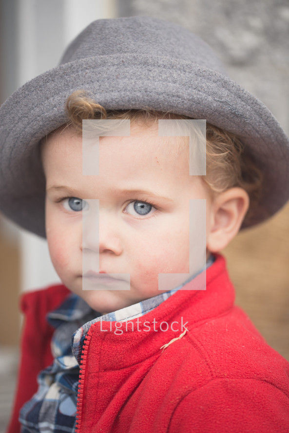 A little boy in a red coat and gray hat.