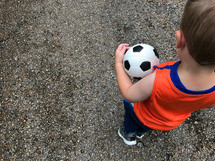 a boy carrying a soccer ball 