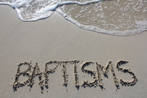 Word 'Baptisms' written in the sand 