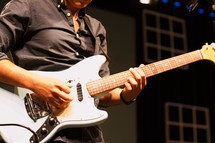 musician playing a guitar on stage in the spot light