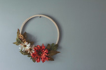 fall wreath with artificial fall flowers hanging on a wall