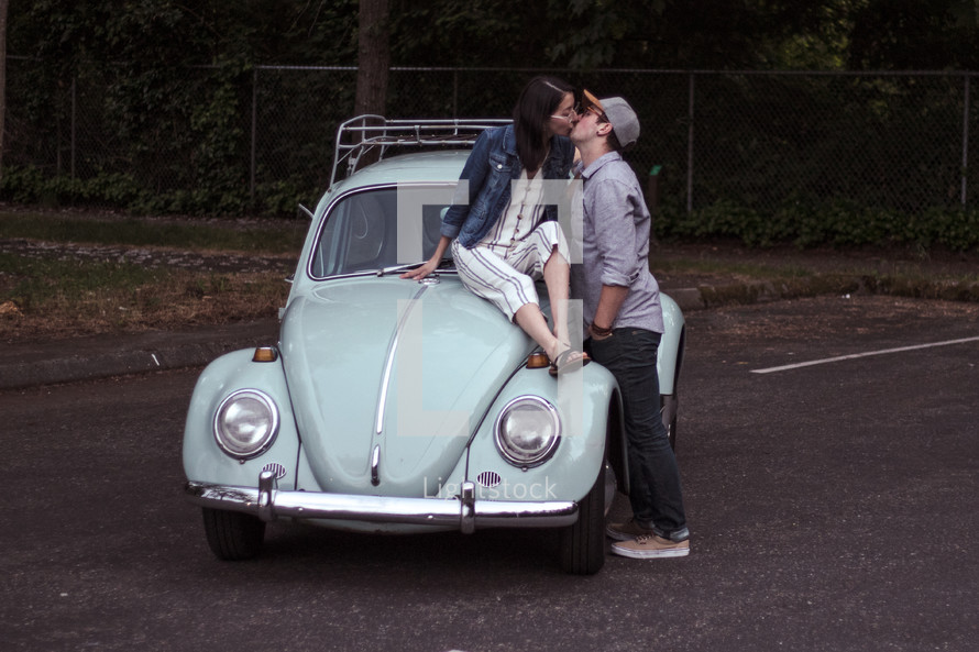 a couple kissing on a vintage Volkswagen Beetle 