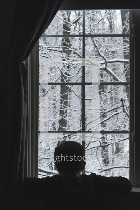 child watching snow out a window 