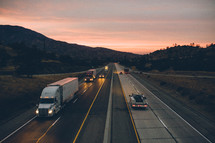 passing cars and semi-truck on a highway at dusk 