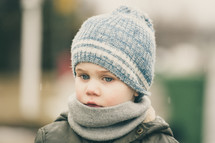 face of a boy child in a scarf and knit cap