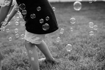 child playing with bubbles in grass 