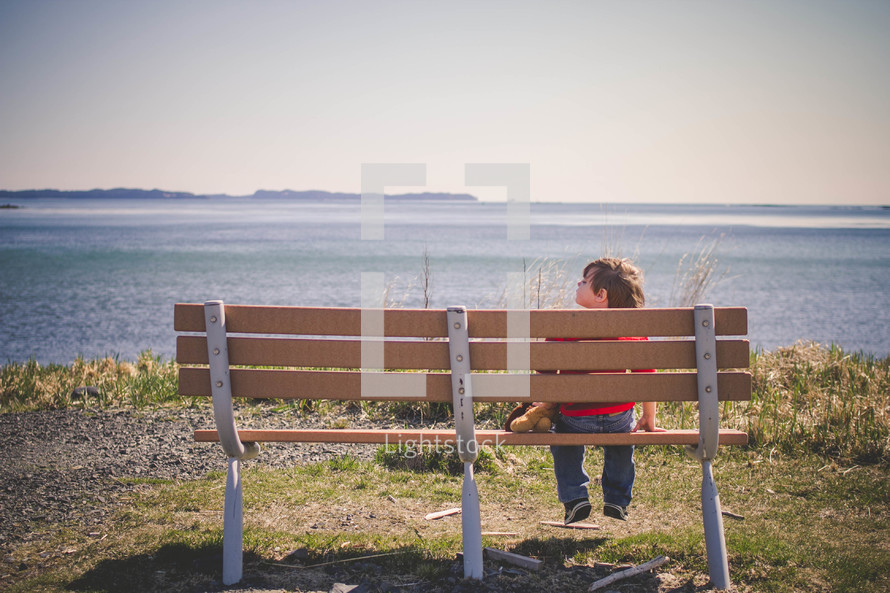 boy child sitting on a park bench 