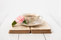 Coffee Cup Sitting on Old French Bible with Pink Camellia on White Background with Room for Text