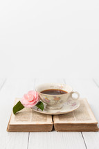 Pink Camellia Beside a Coffee Cup on an Open Bible on White Background with Room for Text