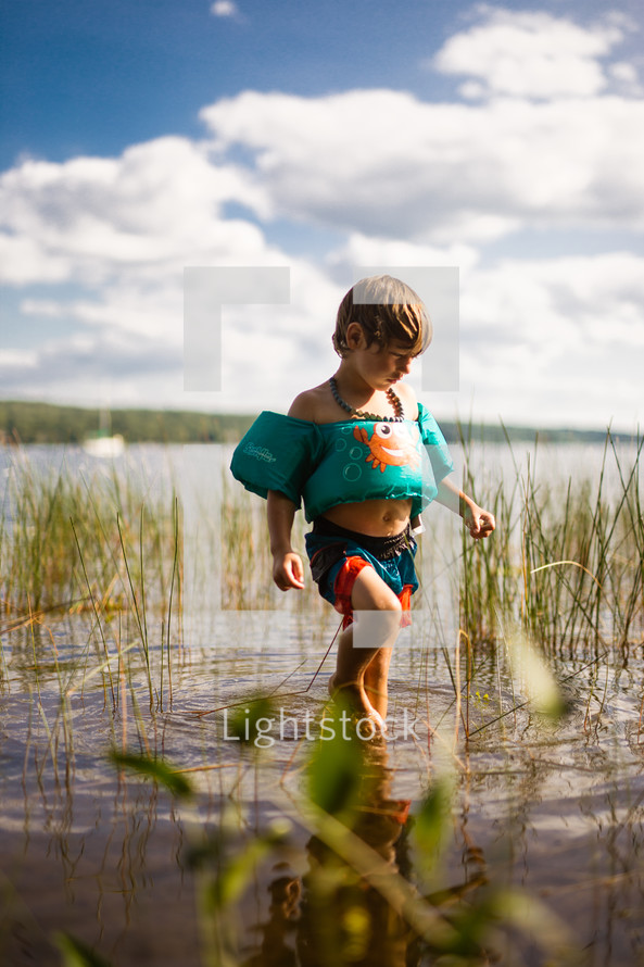 a child in a floatie playing at a lake 