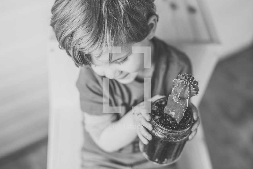 a boy holding a cactus in a mason jar 