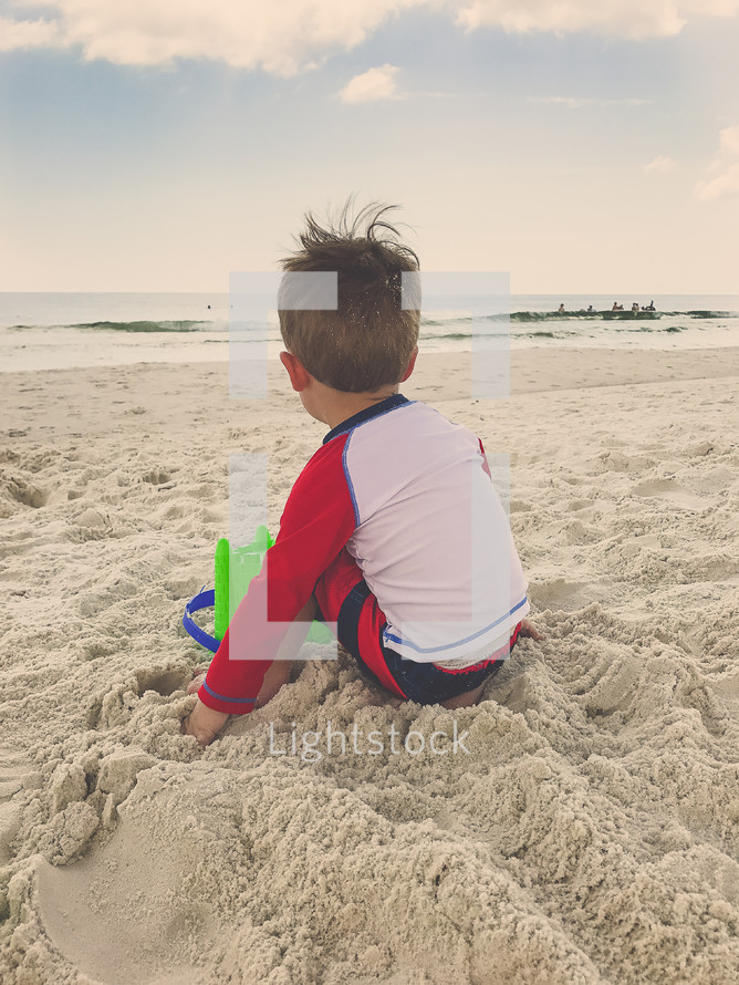 boy playing in the sand on a beach 