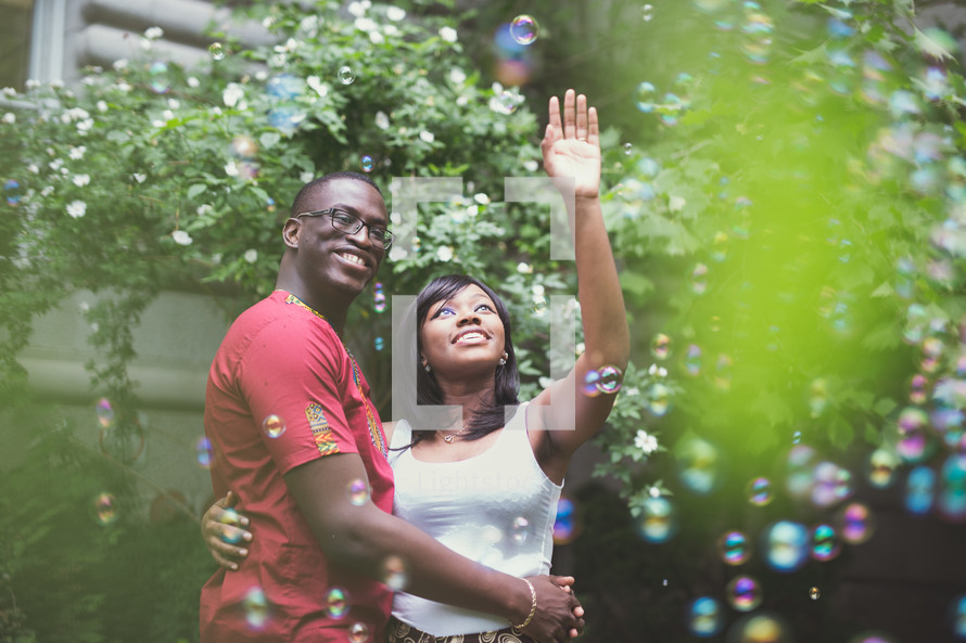 An African American couple in love reaching for bubbles 