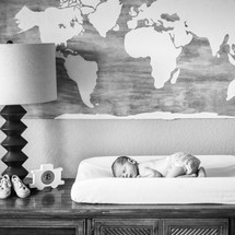 Newborn baby on a changing table under a world map 