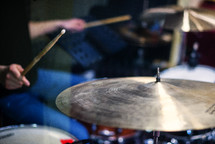 Male drummer with drumsticks playing drums and cymbals