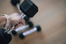 Woman's hand picking up dumbbells