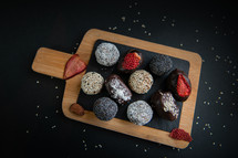 handmade sugar free and gluten free fruit and chocolate candies on a wooden board and black background