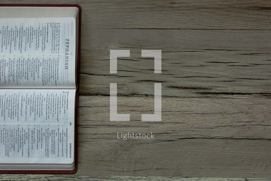 Hebrew Bible open to the Book of Zephaniah on a wooden floor.