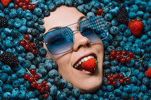 Happy woman face in eyewear fresh ripe berries - blueberries, strawberries