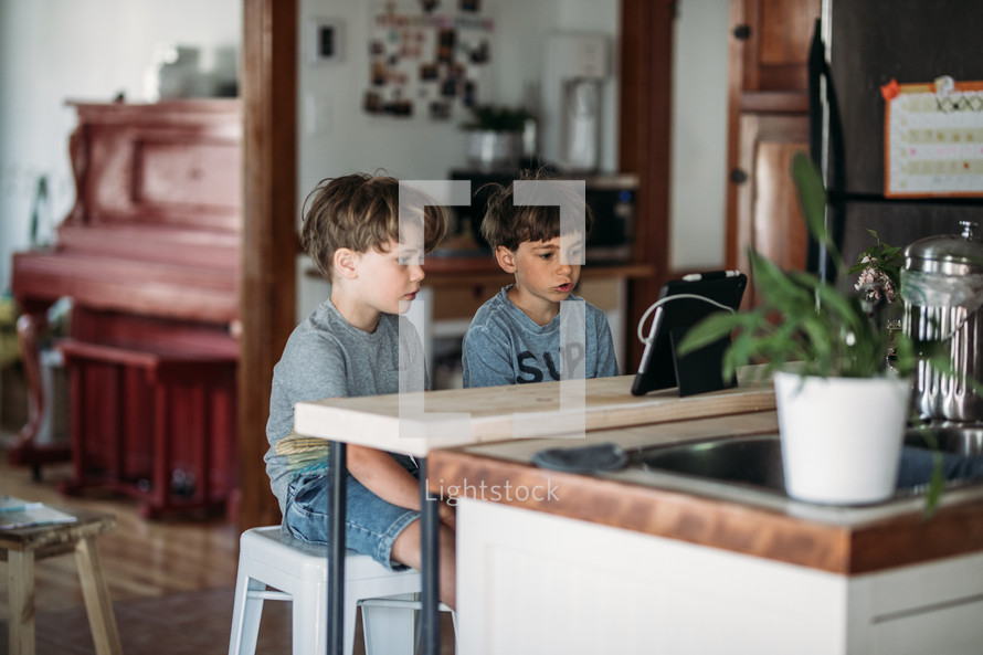 two boys doing a video conference in a kitchen 