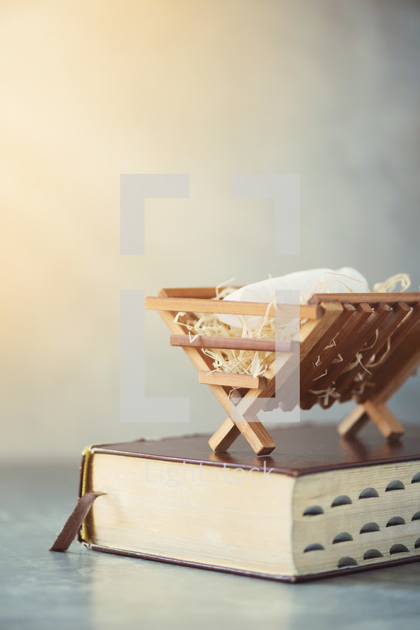 Birth of Jesus Christ. Wooden manger on Holy bible. Christian Christmas concept. Banner, copy space. Nativity scene symbol. Jesus is reason for season. Salvation, Messiah, Emmanuel, God with us, hope