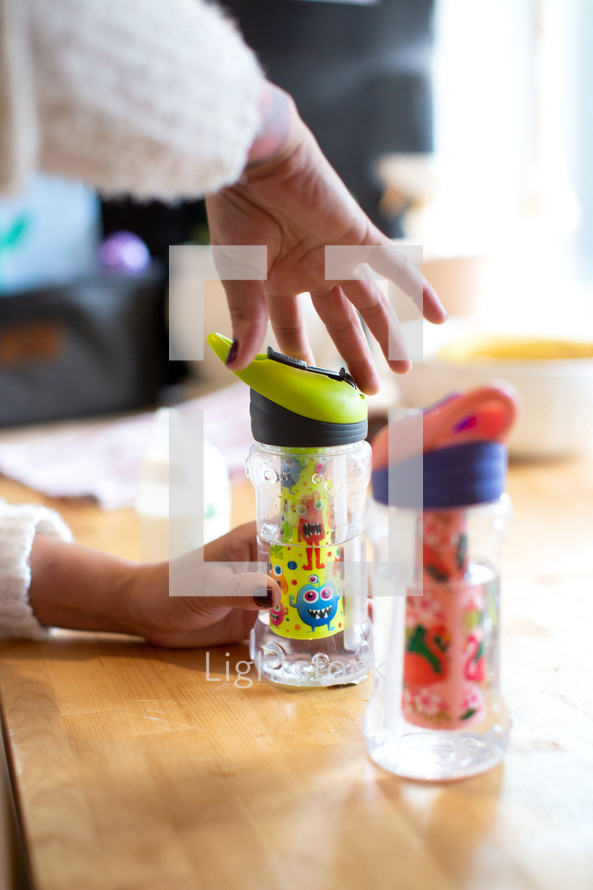 Mom filling sippy cups for children 