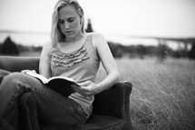 A girl sitting in a chair reading her Bible