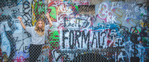 a woman behind a chain link fence and graffiti 