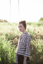 woman in a field of tall grass wearing a flowing shirt 