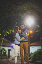 couple standing under a street lamp at night 