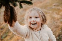 child picking pinecones from a pine tree