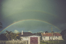 A double rainbow arching over houses.