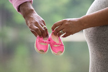 expectant couple holding baby shoes 